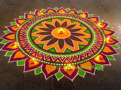 a colorful rangdi design with candles on the ground