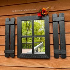 a mirror on the side of a wooden building with an autumn decoration hanging from it