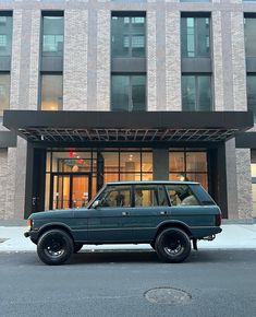 an suv parked in front of a tall building