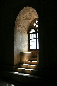 the light shines through an arched window onto some steps that lead up to it