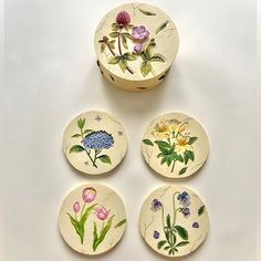 four ceramic coasters with flowers painted on them sitting next to each other in front of a white background