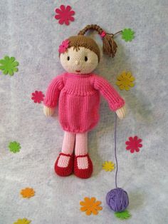 a crocheted doll with a pink sweater and red shoes