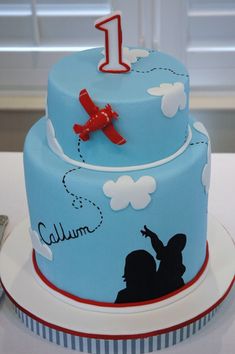 a blue cake decorated with an airplane and the number one