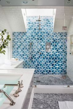 a blue and white bathroom with a skylight above the shower stall, sink and bathtub