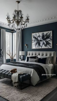 a bedroom decorated in blue and white with a chandelier hanging above the bed