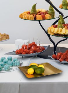 an assortment of desserts are displayed on plates and trays with fruit in them