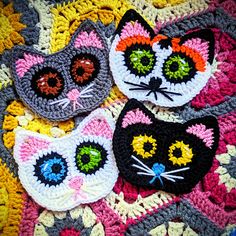 three crocheted cats sitting on top of a colorful blanket next to each other