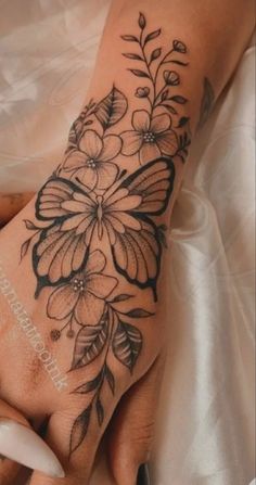 a woman's hand with tattoos on it and flowers in the middle of her arm