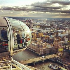 people are standing on the top of a ferris wheel in london, looking out over the city