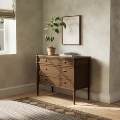 a plant is sitting on top of a dresser in a room with white walls and wooden floors