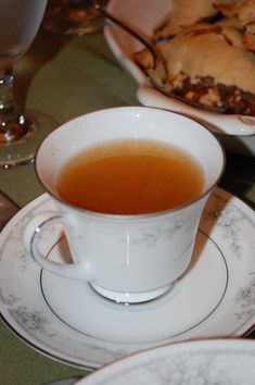 a cup of tea sitting on top of a saucer next to a plate filled with food