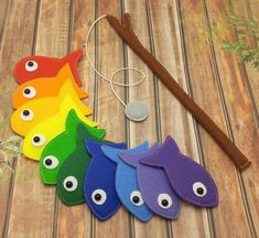 five different colored fish shaped key fobs next to a wooden stick with an eyeball on it