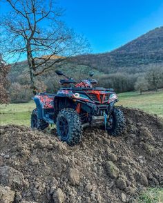 an atv is parked on top of a pile of dirt in the middle of a field