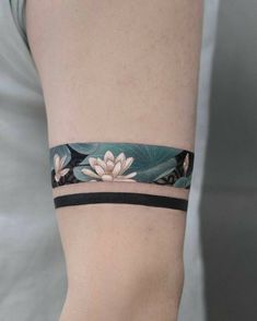 a woman's arm with white flowers and leaves on the wristband, while wearing a gray shirt