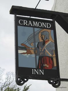 a sign hanging from the side of a building that says cramond inn in front of it