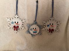 three snowflake ornaments hanging on a towel in the bathroom, one is wearing a red bow