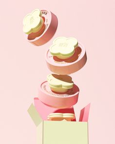 three donuts are stacked on top of each other in pink boxes with white frosting and sprinkles