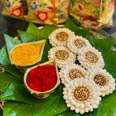 colorful powders are arranged on top of leafy green leaves and decorated with flowers