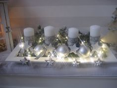 a table topped with candles and ornaments on top of a white tray covered in lights