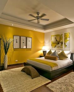 a bedroom with yellow walls and white bedding, carpeted flooring and ceiling fan