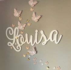 a wall with butterflies and the word louisa written in cursive letters on it