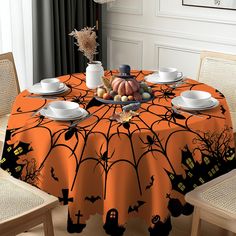 an orange table cloth with black spider webs and pumpkins is on the dining room table