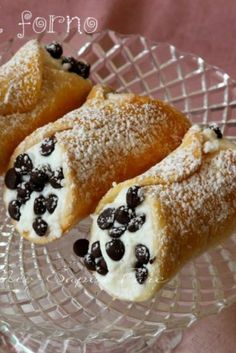 two pastries with blueberries and powdered sugar on a glass plate