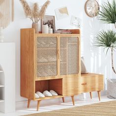 a wooden cabinet sitting next to a plant in a living room filled with furniture and decor