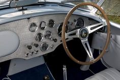 the interior of an old car with wood steering wheel