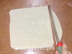 a person cutting up food on top of a wooden table next to a pair of scissors