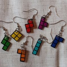 six pairs of earrings made out of rubikt cubes on a white cloth