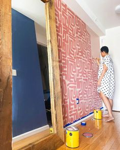 a woman is painting a wall with red and blue paint