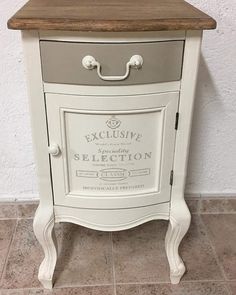 an old fashioned white and grey cabinet with wood top on tile floor next to wall