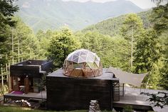 a wooden structure with a glass dome on top in the middle of a wooded area