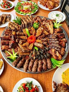 a large platter filled with meat and vegetables on top of a wooden dining table