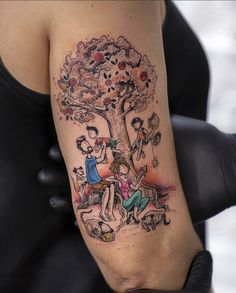 a woman with a tattoo on her arm is sitting in front of a tree and two children