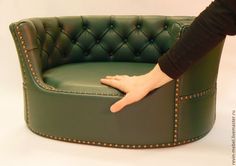 a person's hand resting on the arm of a green leather chair with studded trim