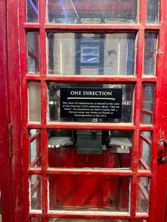 a red phone booth with one direction sign on it