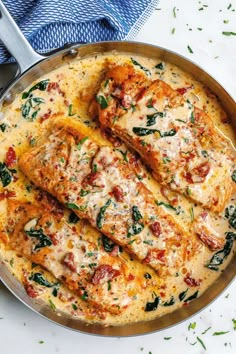 a pan filled with chicken covered in cheese and spinach on top of a table