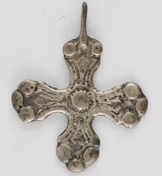 an old silver cross with holes in the center on a white background, it appears to have been made from metal