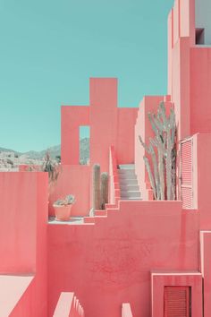 a pink building with stairs and cactus trees