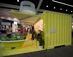 people are standing around in front of a yellow container and green couches on display