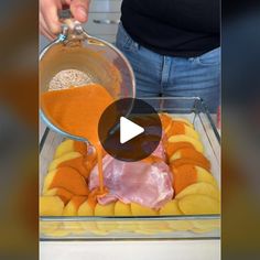 a person pouring sauce on food in a glass container with fruit and vegetables around it