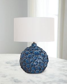 a blue vase sitting on top of a table next to a white lampshade