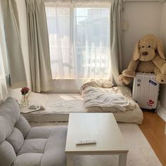 a teddy bear sitting on top of a bed next to a white table and couch