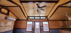 a ceiling fan in the middle of a room with wood paneling on the walls