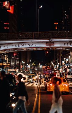 a busy city street at night with cars and pedestrians