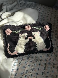 a crocheted cat pillow on a bed with white sheets and blue floral pillows