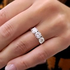 a woman's hand with a three stone ring on top of her wedding band