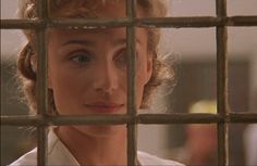 a woman looking through the bars of a jail cell